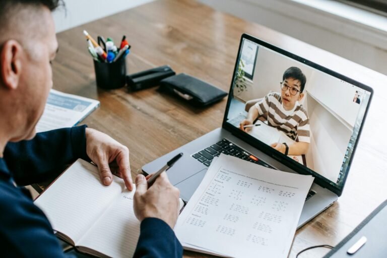 Adult engaged in a virtual learning session via video call on a laptop, indoors.